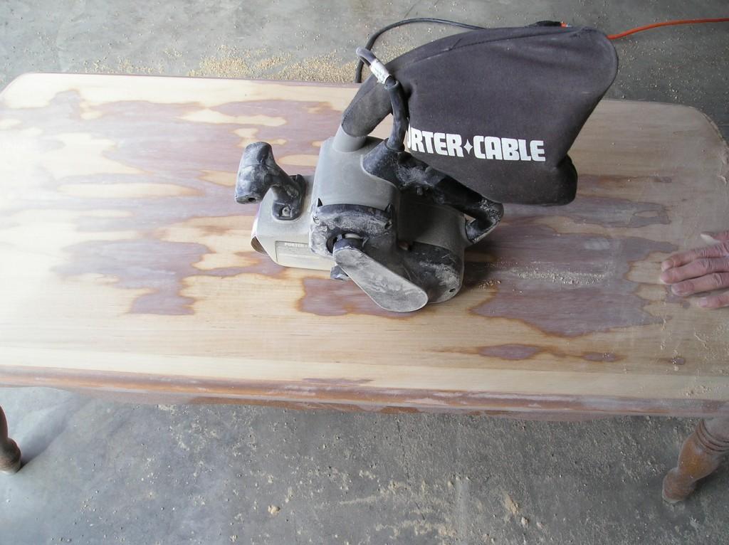 Sanding the coffee table top with belt sander.